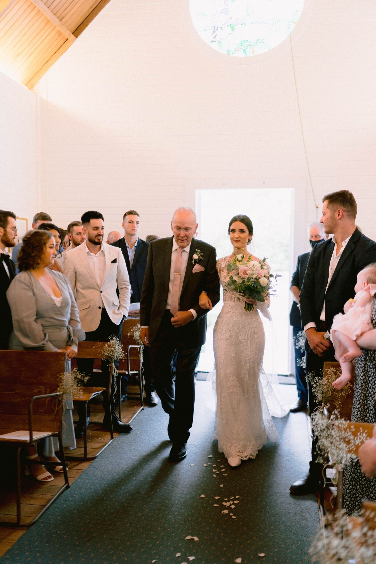 Wedding ceremony guests seated in rows of wooden pews during an indoor celebration.
