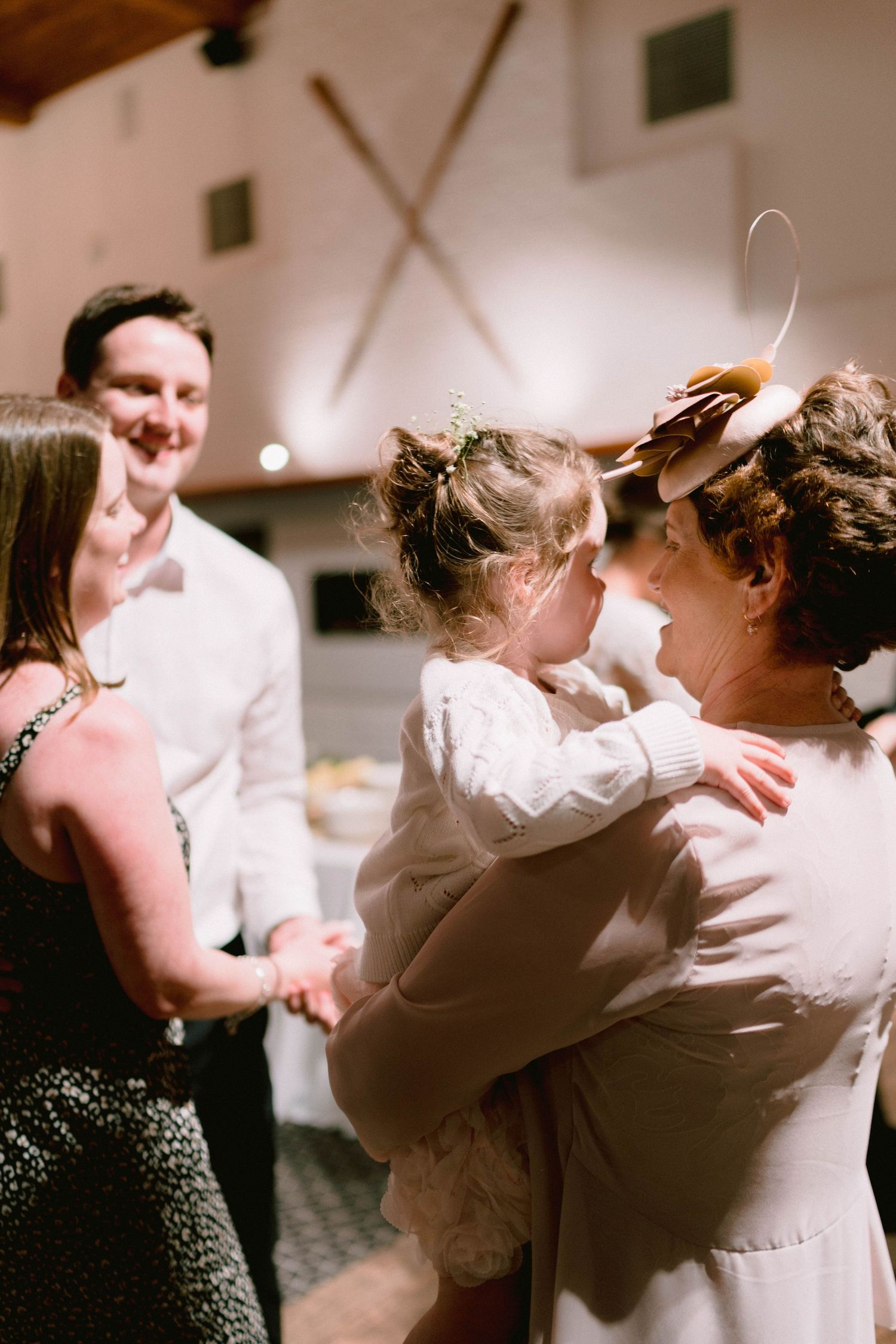 Guests share intimate moments during a wedding reception in a rustic venue with wooden beams.