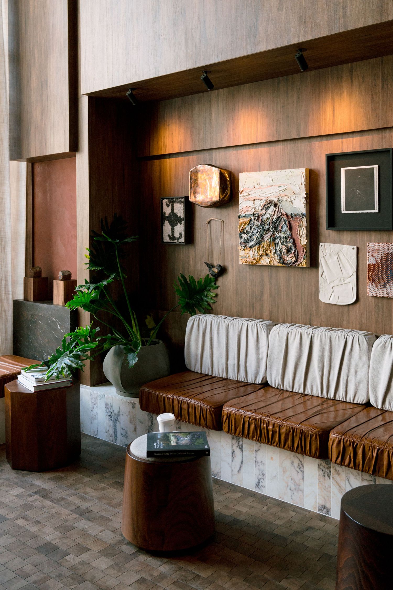 Modern lounge area with bench seating, wood paneling, and decorative wall hangings in warm tones.
