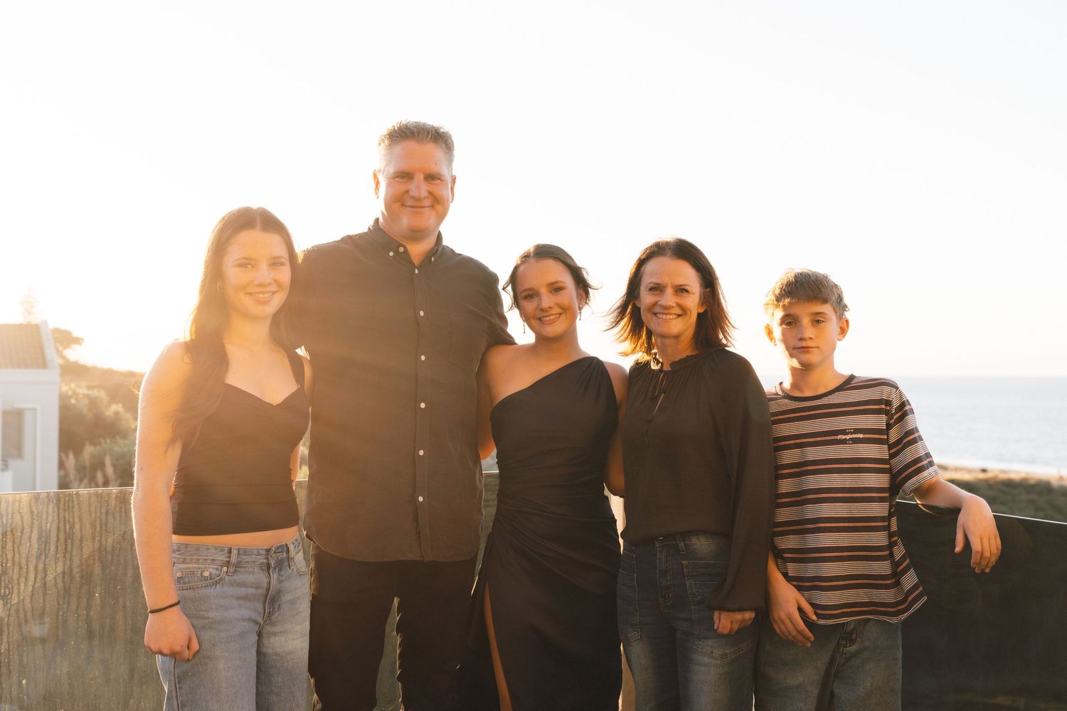 Family group poses together against sunset backdrop during golden hour outdoor photoshoot.