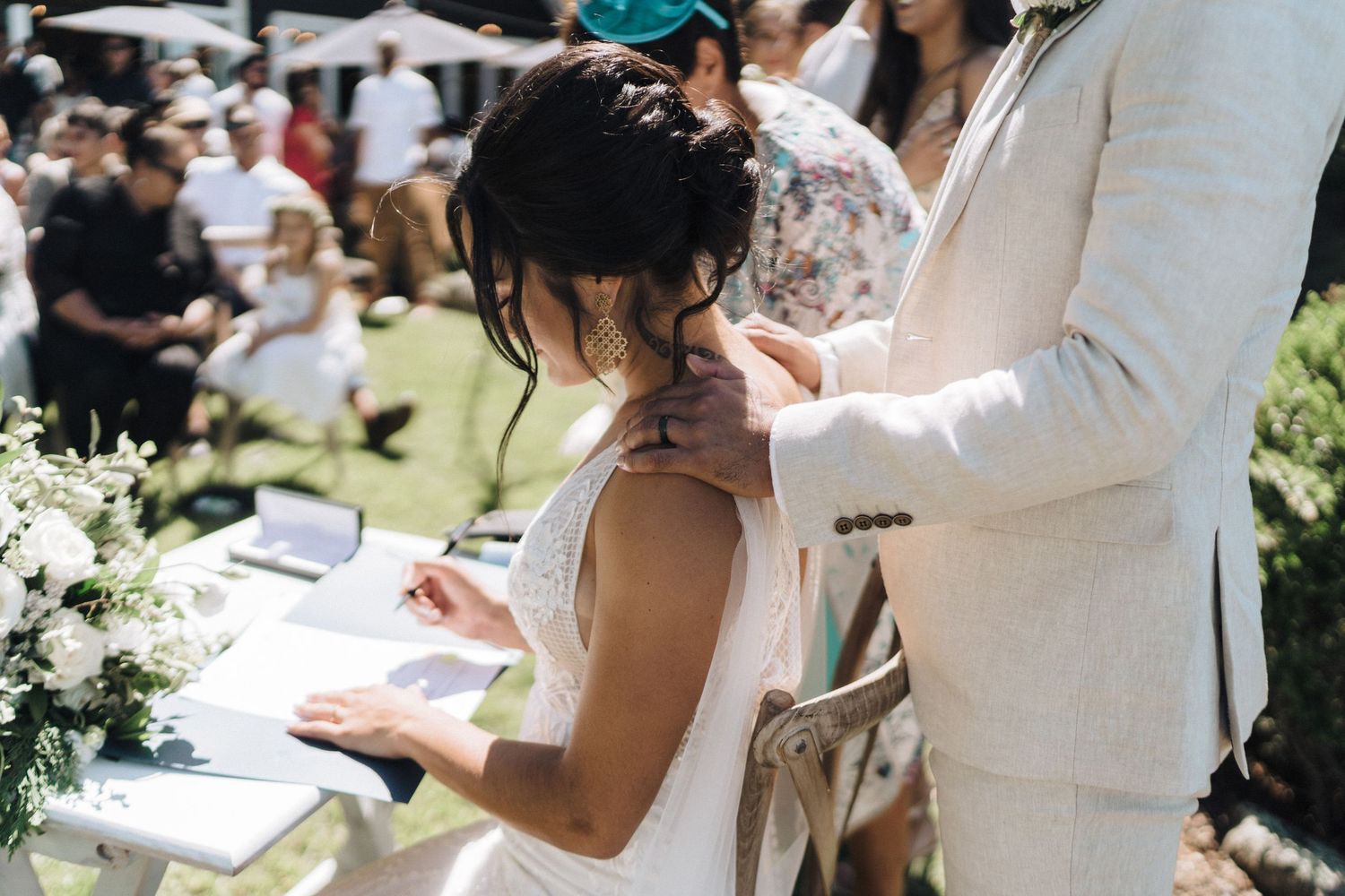 Wedding ceremony moment captured outdoors with light colored floral decorations.