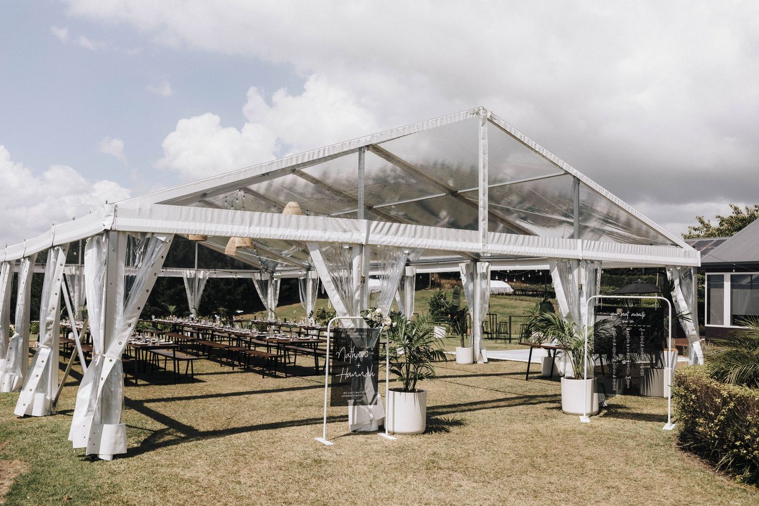 Large white wedding tent setup with multiple sections under cloudy sky.