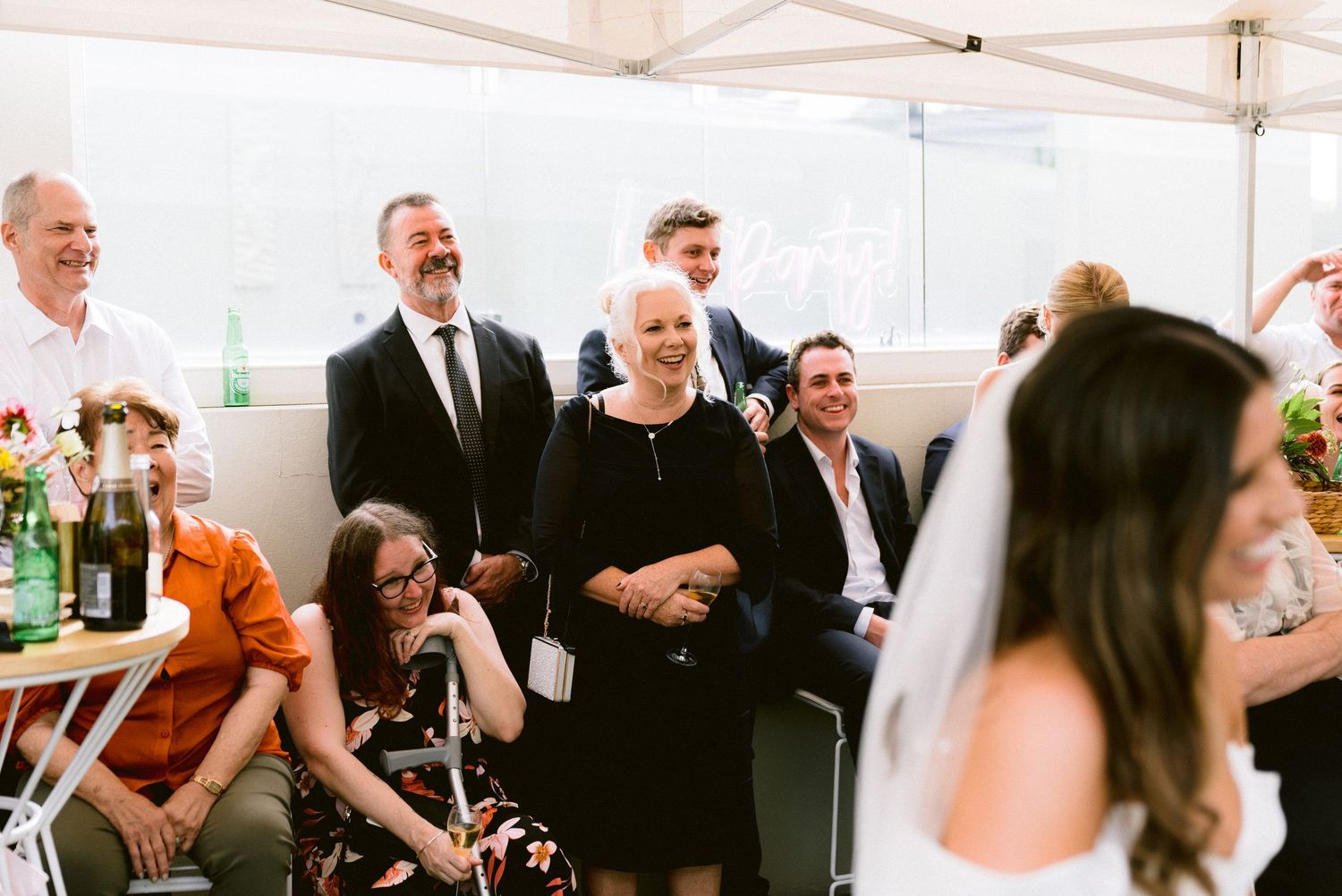 Wedding guests enjoy the celebration under a white tent during the reception.