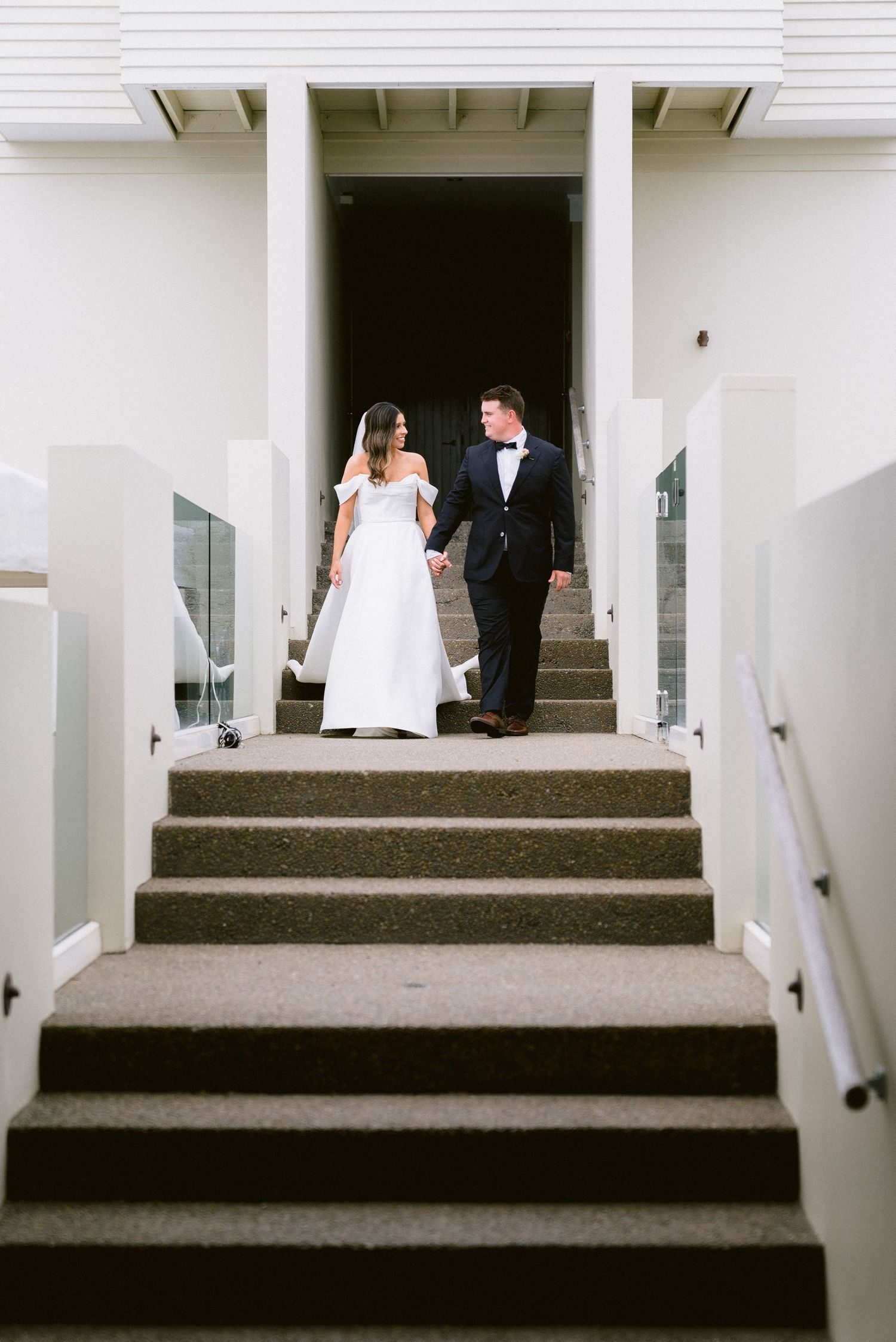 Modern white building entrance with a series of concrete steps showcasing a formal wedding occasion.