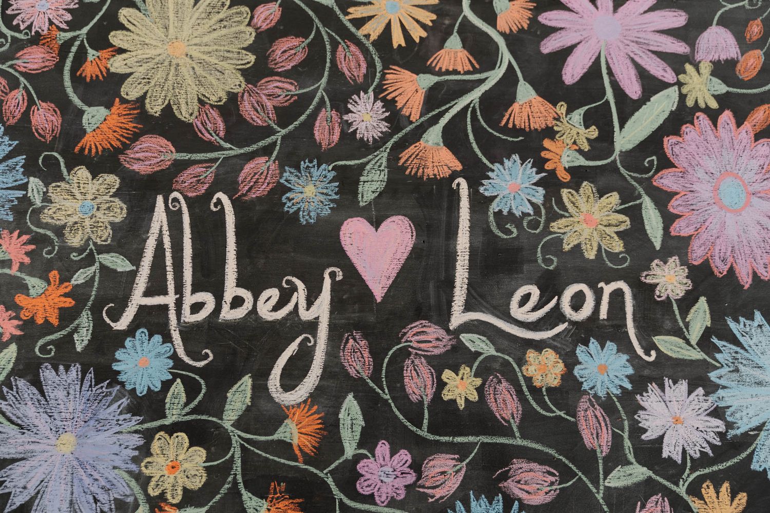 Handwritten text surrounded by colorful floral illustrations on a dark chalkboard background.