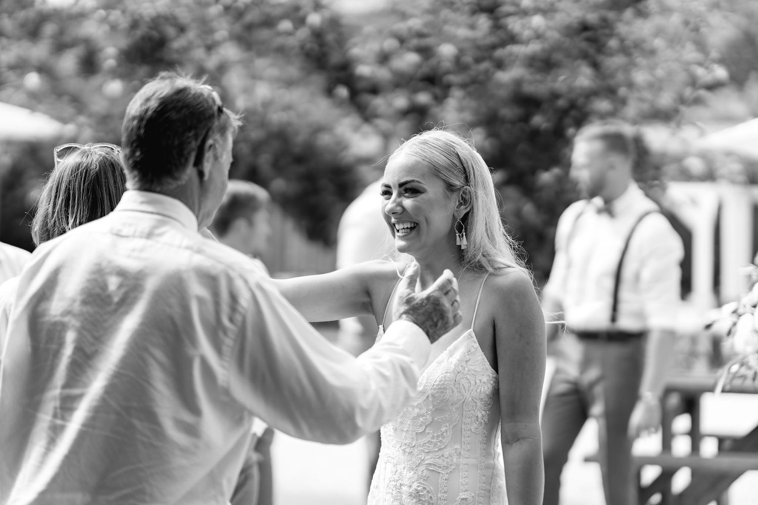 Wedding guests celebrate and dance together at an outdoor reception during a joyful summer celebration.