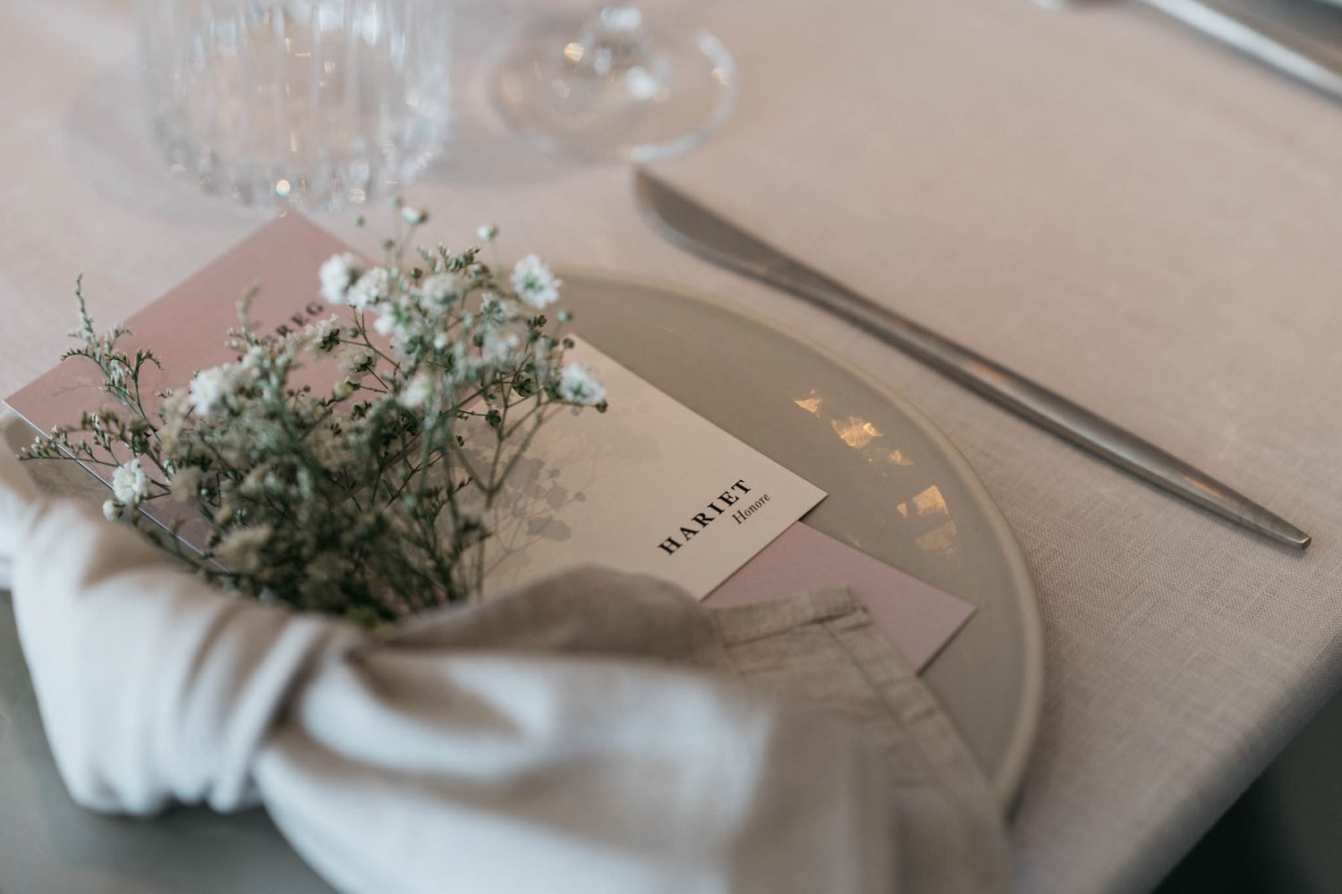 Elegant table setting with baby's breath flowers, place card, and napkin in muted tones.