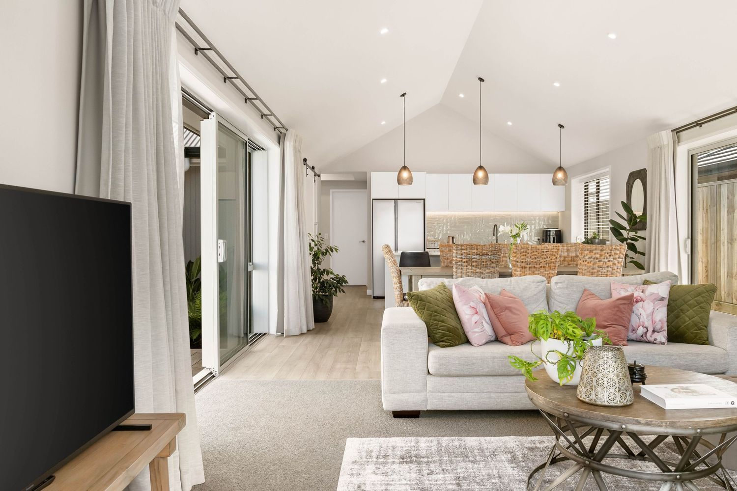Bright modern living room with white furniture, decorative pillows, and natural lighting.