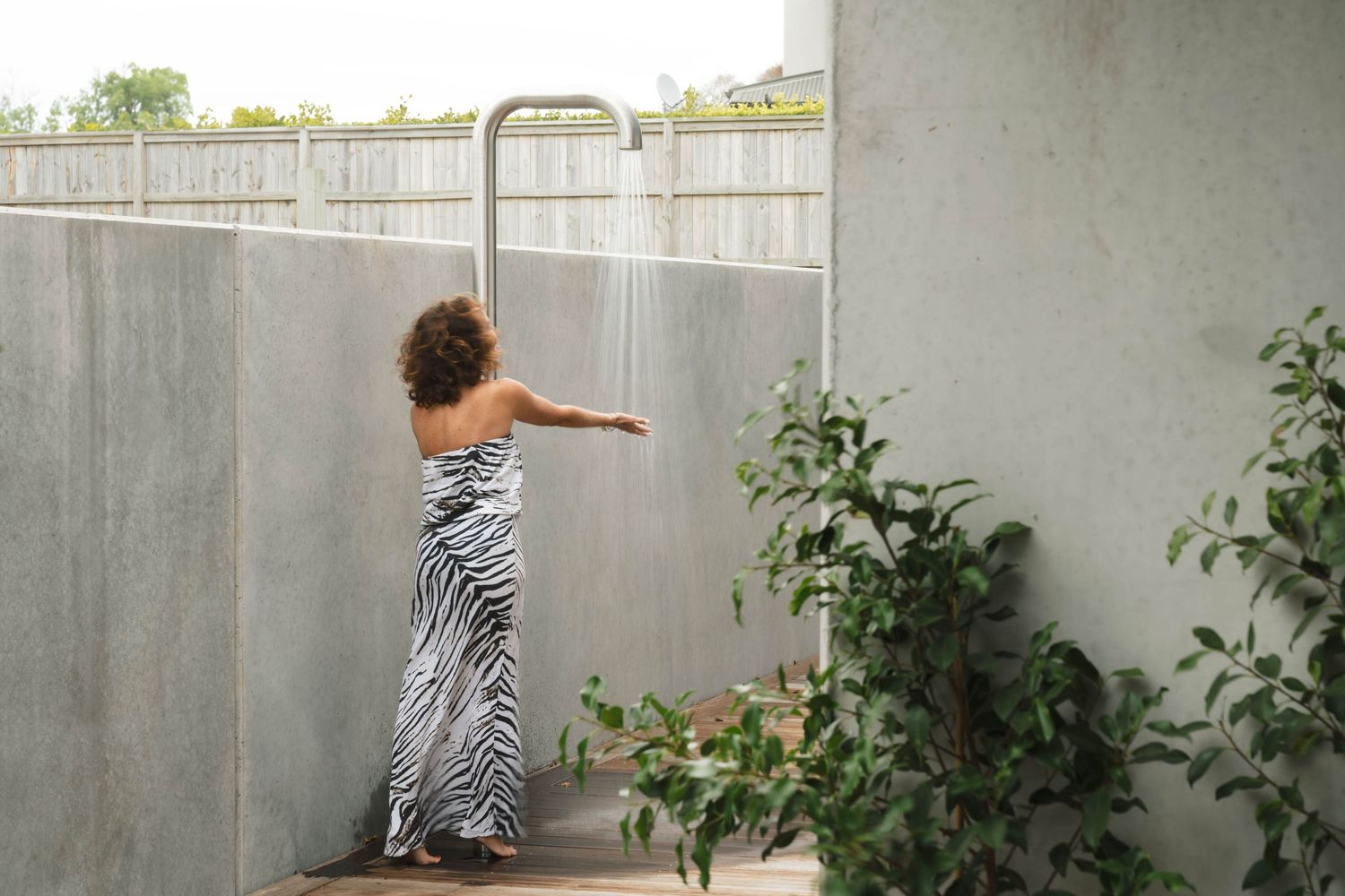 Modern concrete courtyard with white walls and green plants creating an outdoor living space.