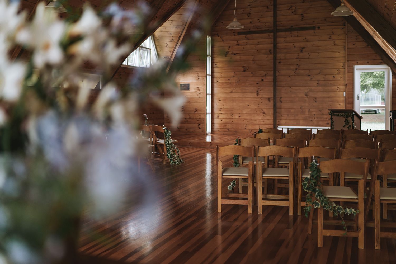Rustic wooden interior of a chapel with wooden chairs and natural light streaming through windows.