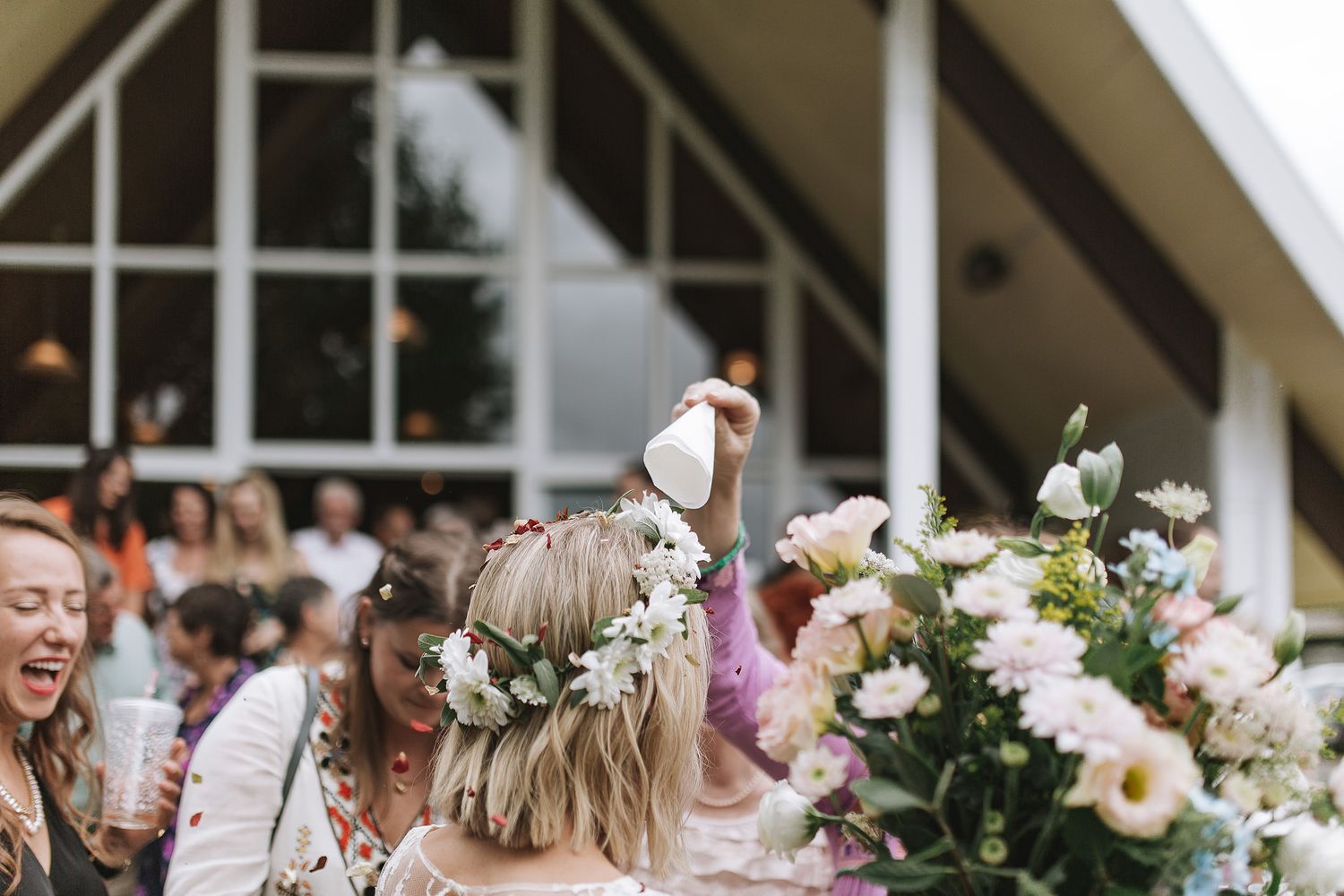 Wedding guests celebrate and blow bubbles during an outdoor celebration with floral arrangements and decorative elements.