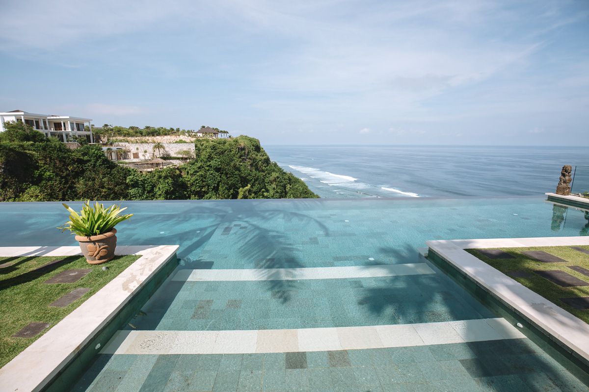 Infinity edge pool overlooking ocean cliffs with stunning coastal views and blue sky.