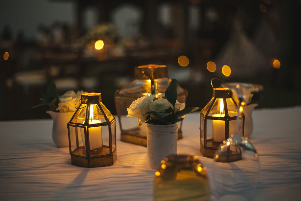 Golden lanterns and floral centerpieces create romantic wedding table decor in dim lighting.