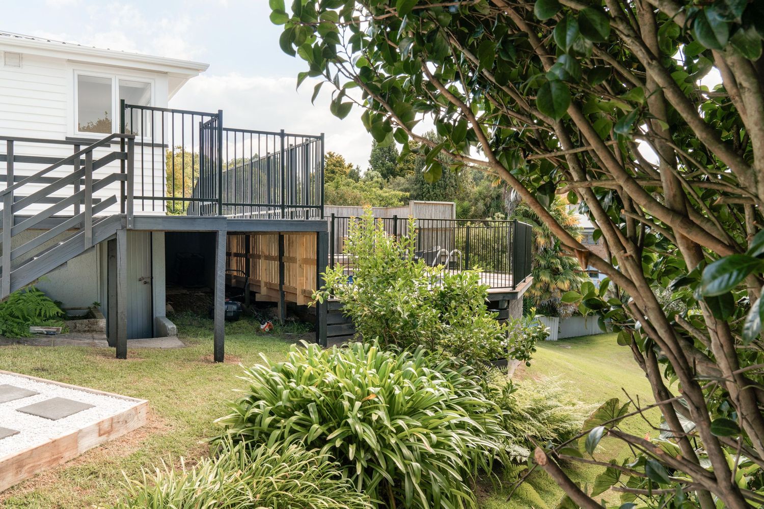 Lush garden landscaping with tropical plants and trees surrounds a modern property.