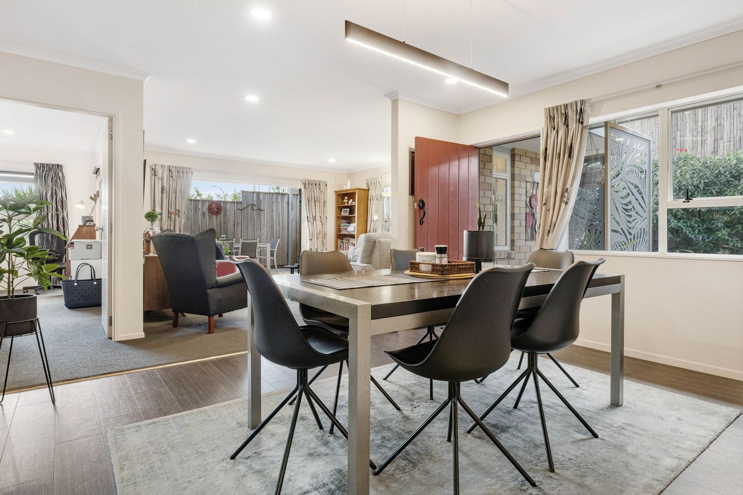 Contemporary dining room with black chairs and wooden table set against large windows with natural light.