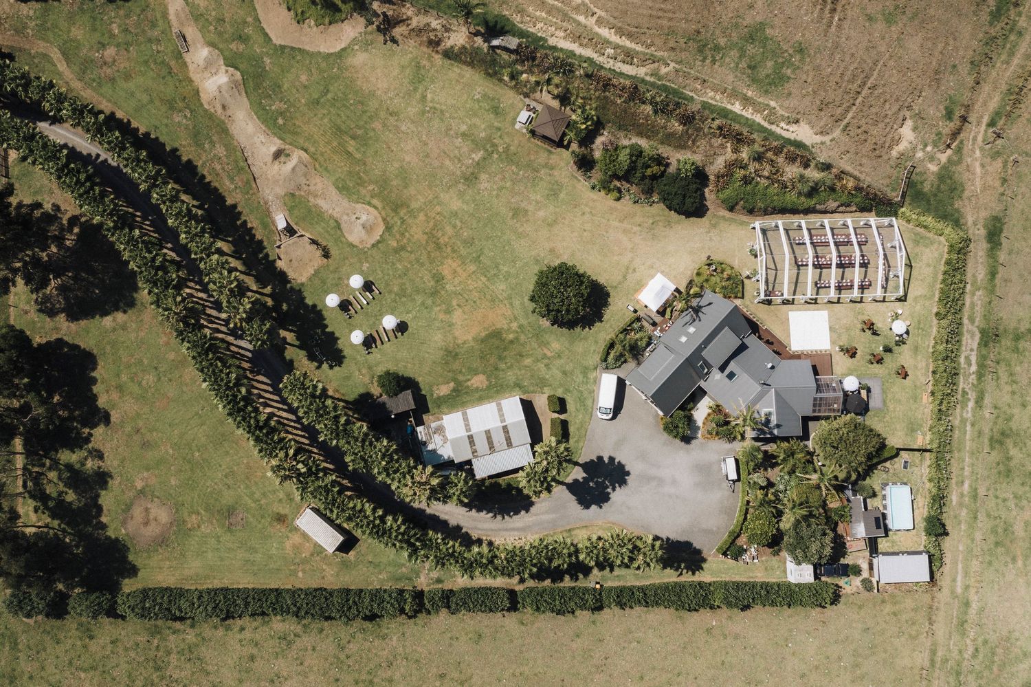 Aerial view of rural property with buildings and winding driveway surrounded by green fields.