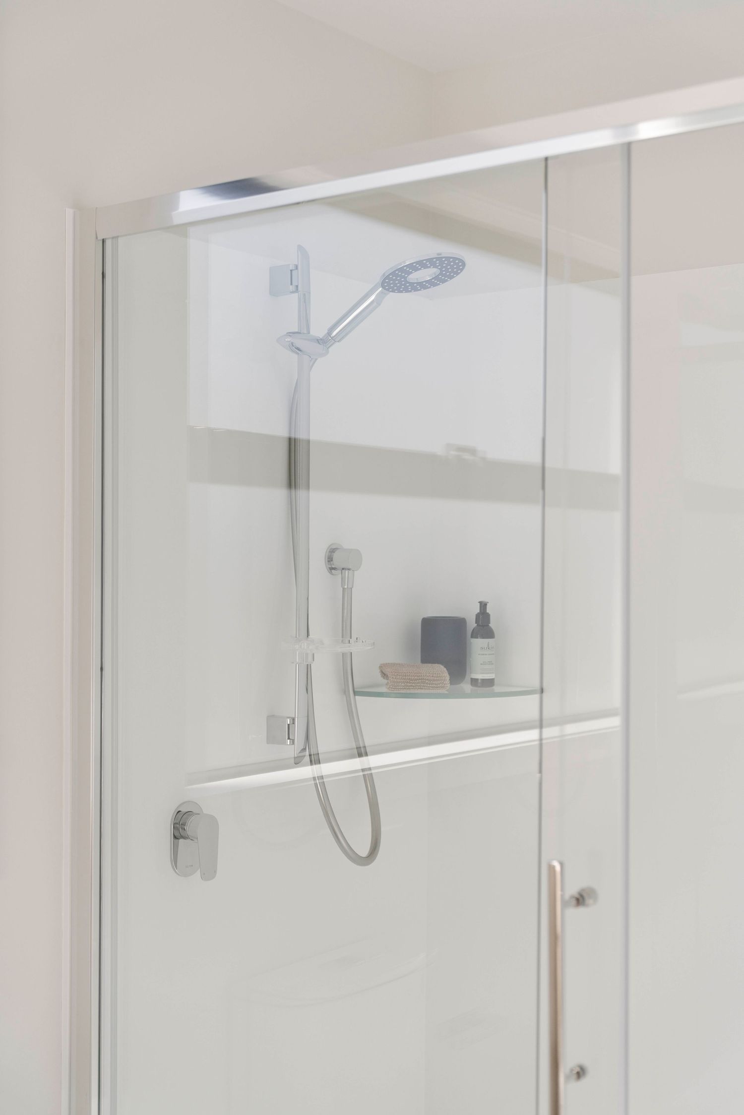 Modern bathroom interior featuring frameless glass shower enclosures with chrome fixtures and minimalist design.