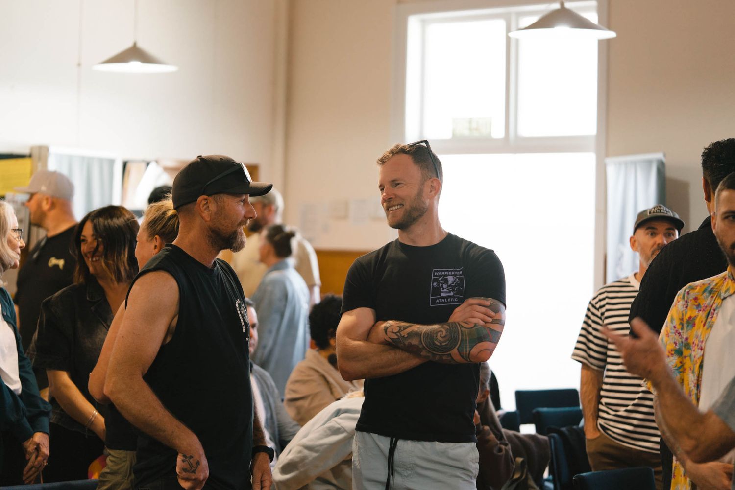 A group of people gathering in a bright church hall during a social event.