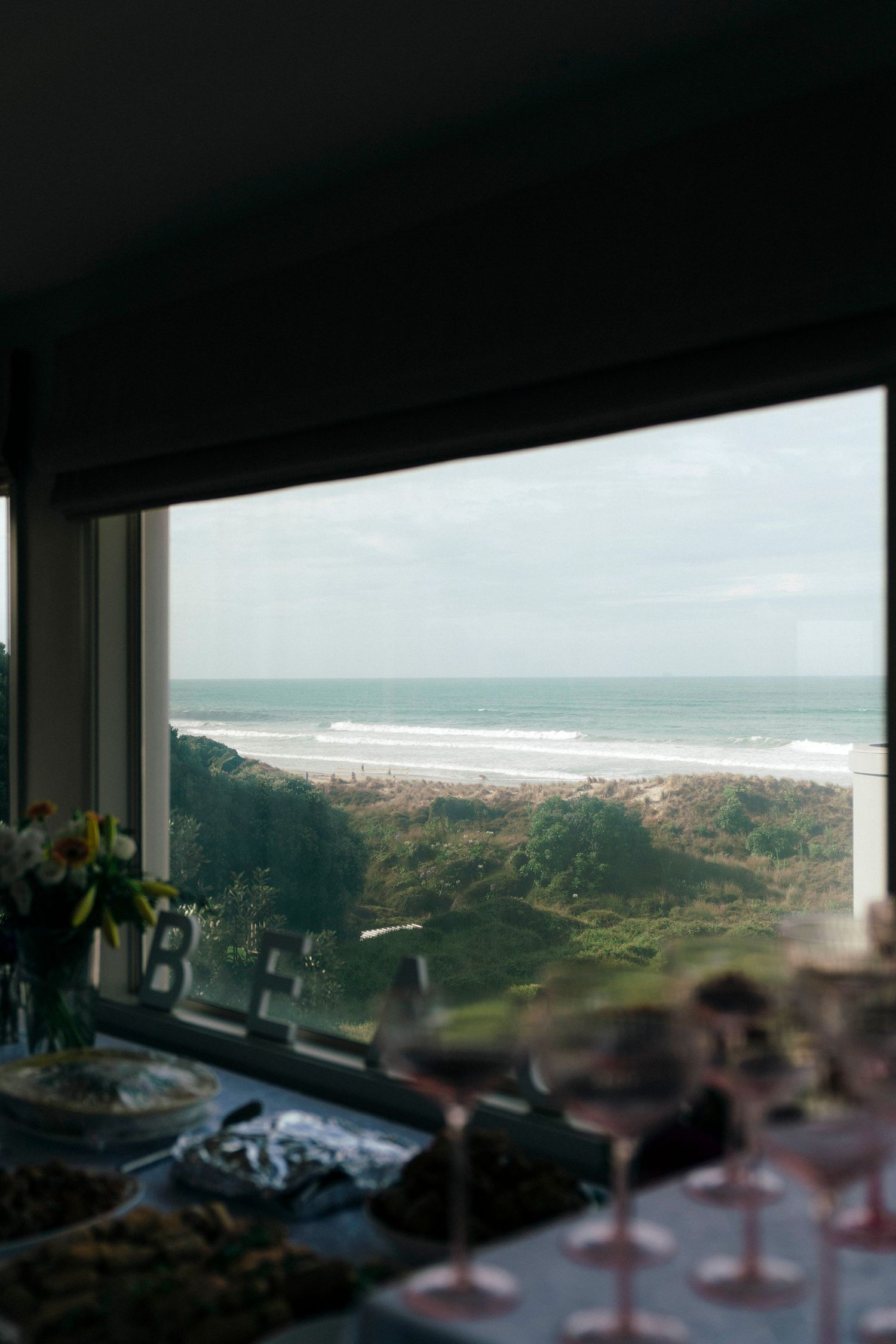 An elegant oceanfront reception table setting with a stunning coastal view through large windows.