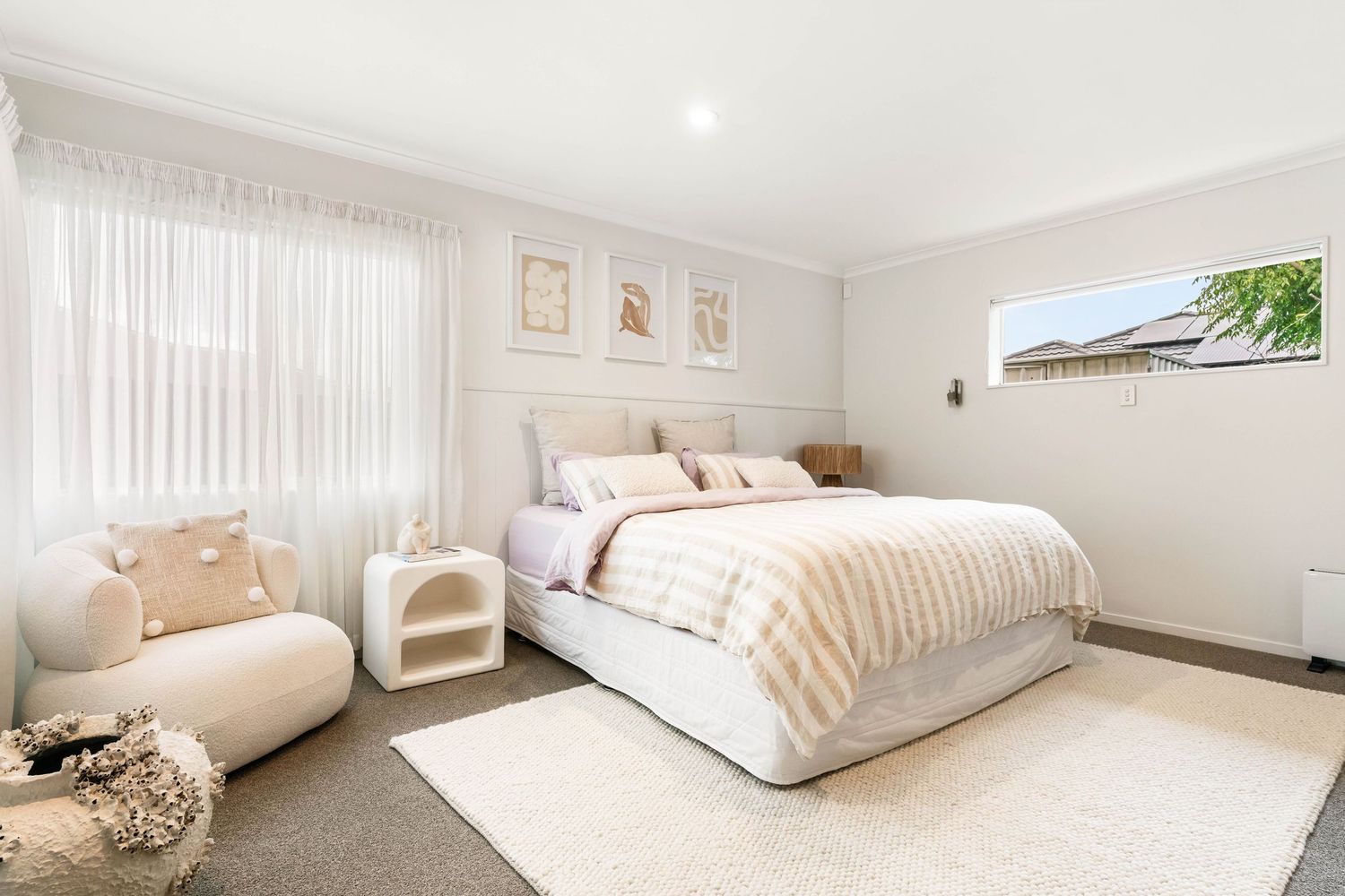 Modern white bedroom interior with minimalist decor, plush bedding, and warm neutral color palette.