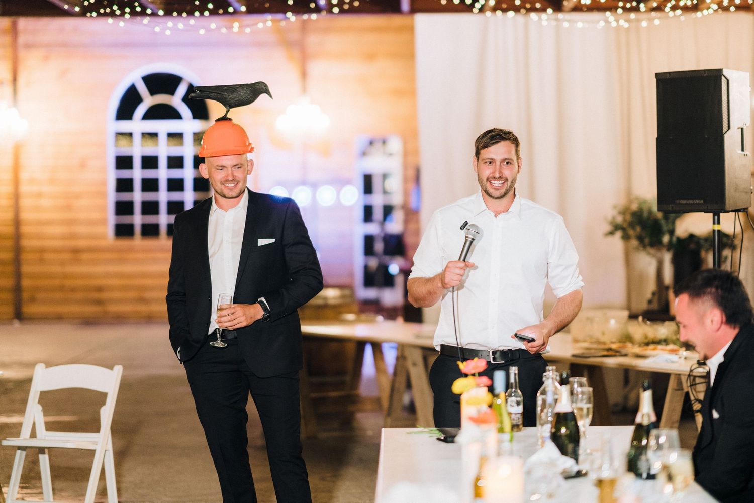 Wedding guests in formal attire giving speeches during an indoor reception.