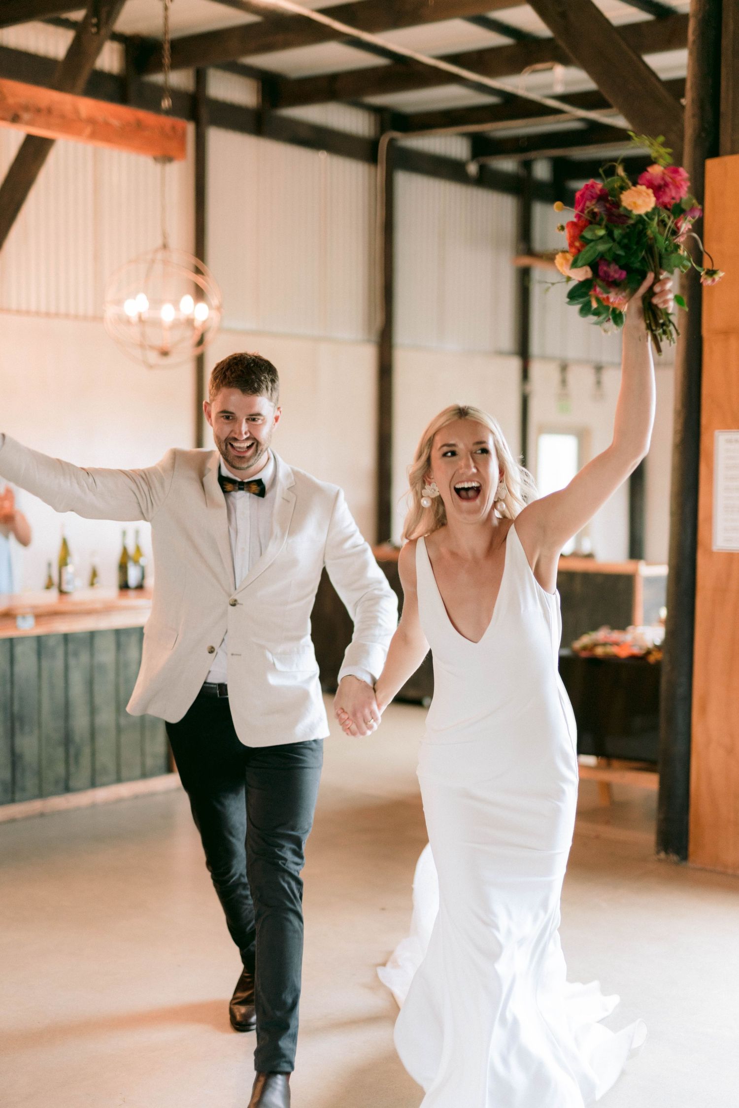 Joyful celebration moment of newlyweds running through an industrial-style reception venue.