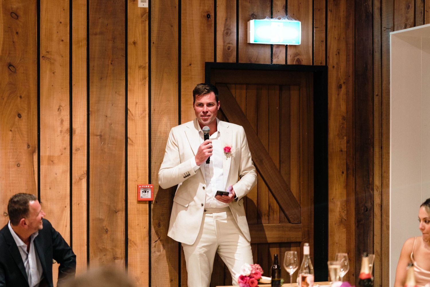 Wedding reception speeches and toasts in rustic wooden venue.