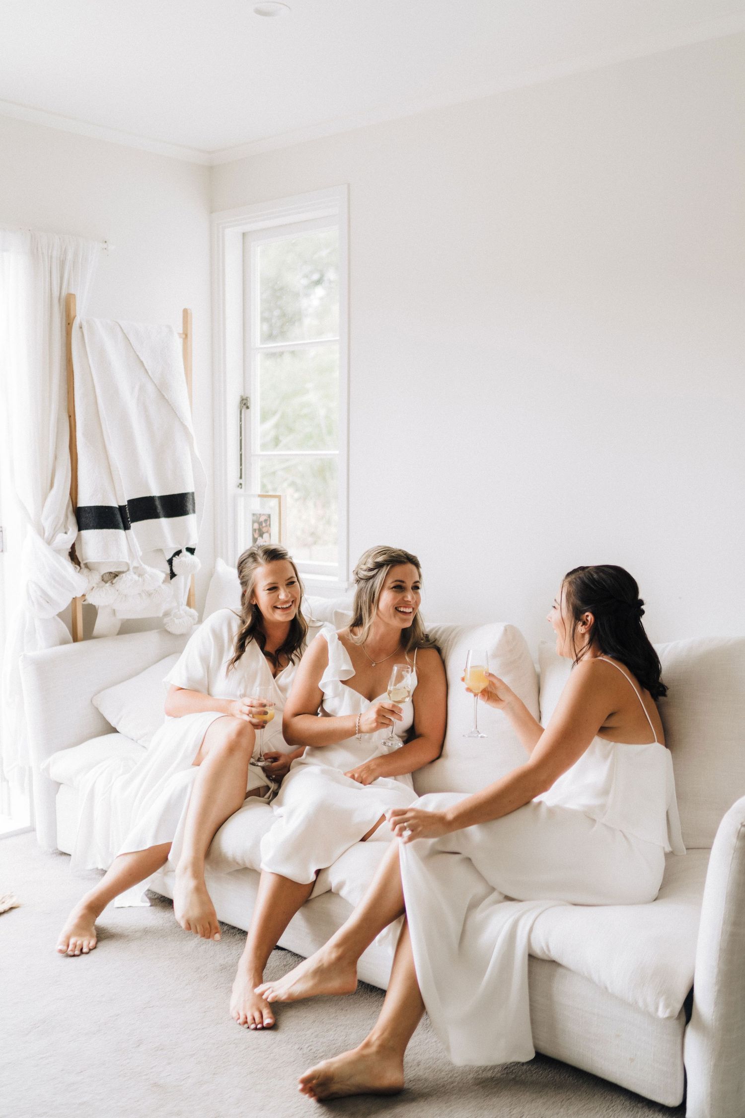 People relaxing together on a white couch in a bright, airy room.