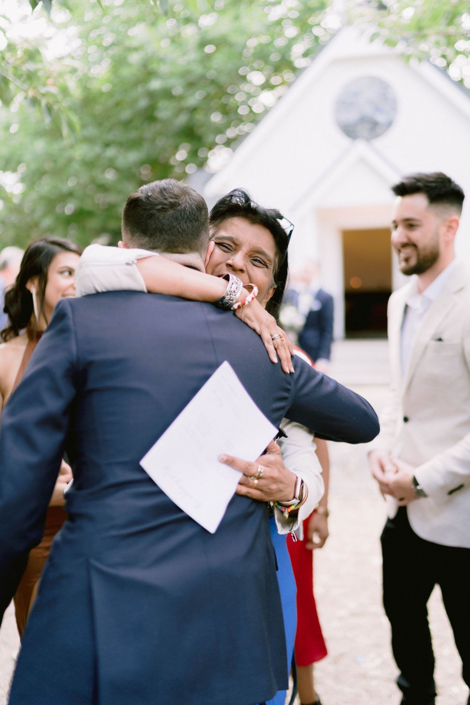 Wedding guests embracing at an outdoor celebration with laughter and joy.