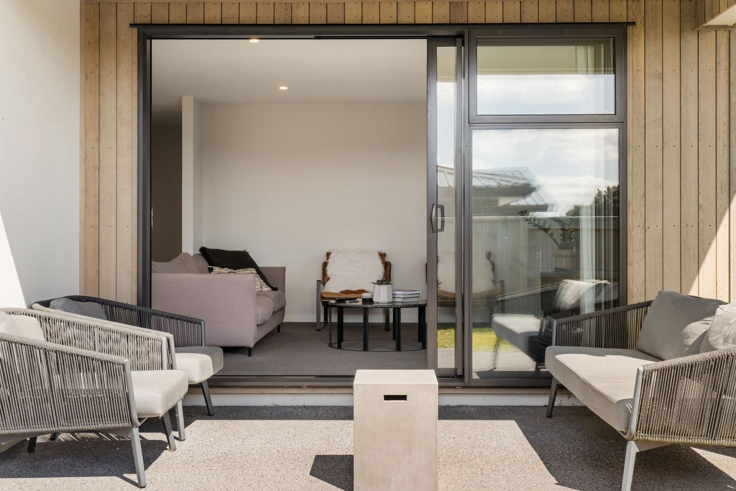 Modern luxury apartment interior with gray furniture, floor-to-ceiling windows, and minimalist decor in warm neutral tones.