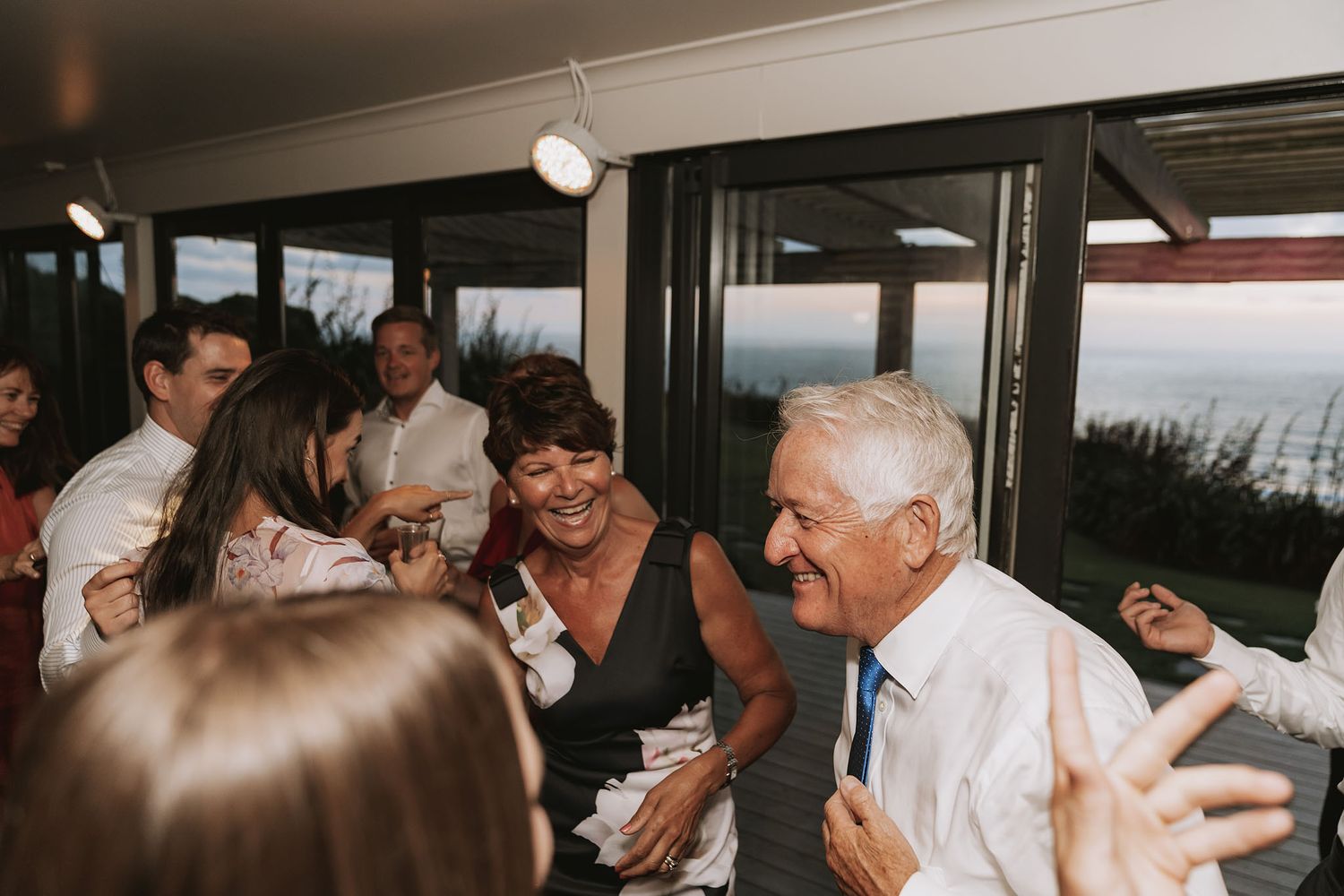 Wedding guests enjoying dances and socializing in a spacious reception venue with modern interior design.