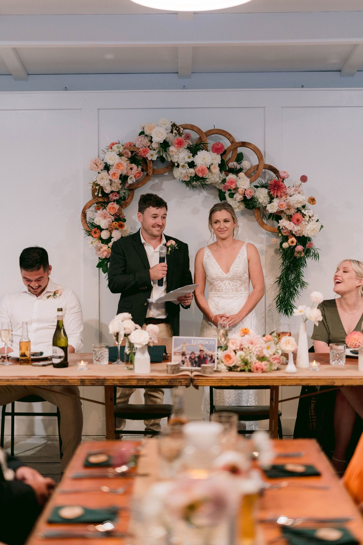 Wedding reception dinner setup with floral arch centerpiece and decorated dining tables.