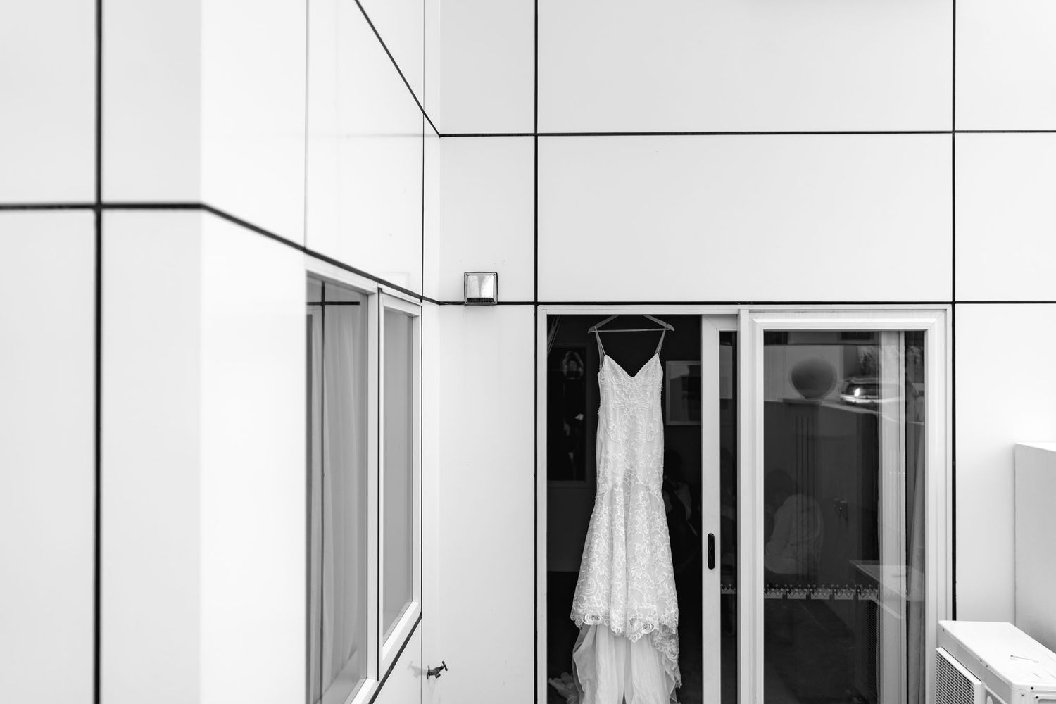 A modern white apartment building facade with glass balconies and floor-to-ceiling windows in an urban setting.