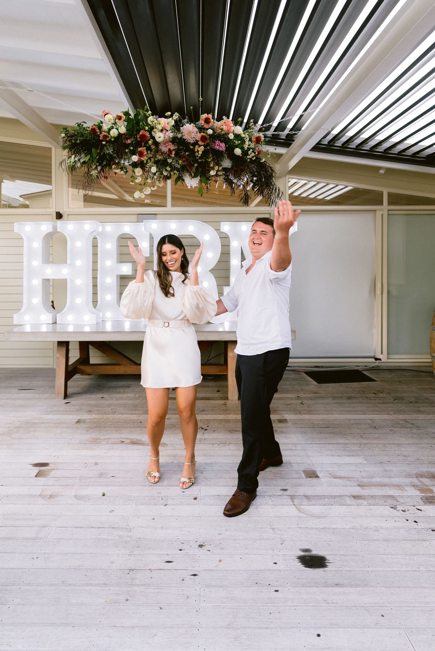 White minimalist indoor space decorated with hanging floral arrangements for a wedding celebration.