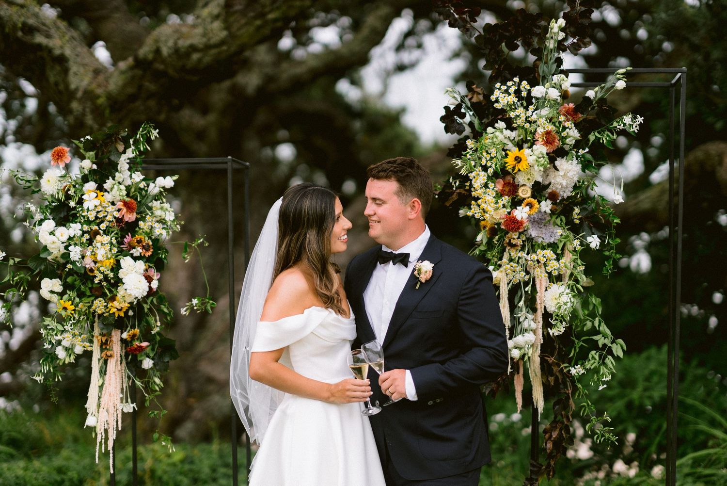 A wedding ceremony setup with a floral arch and natural greenery backdrop.