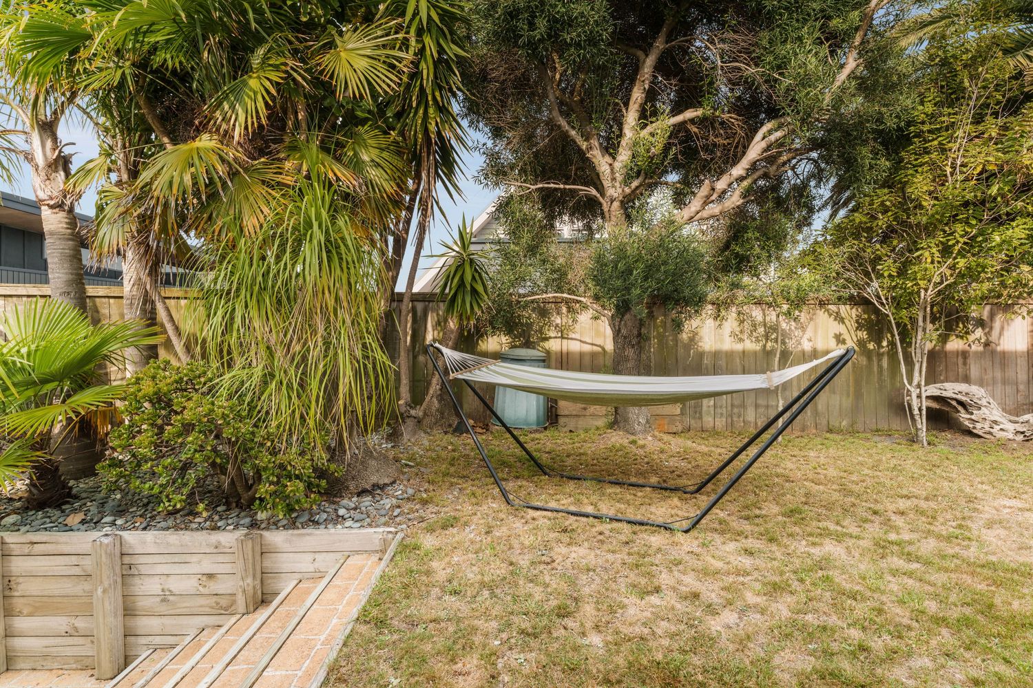 Lush tropical garden landscape with palm trees and natural wooden pathways.