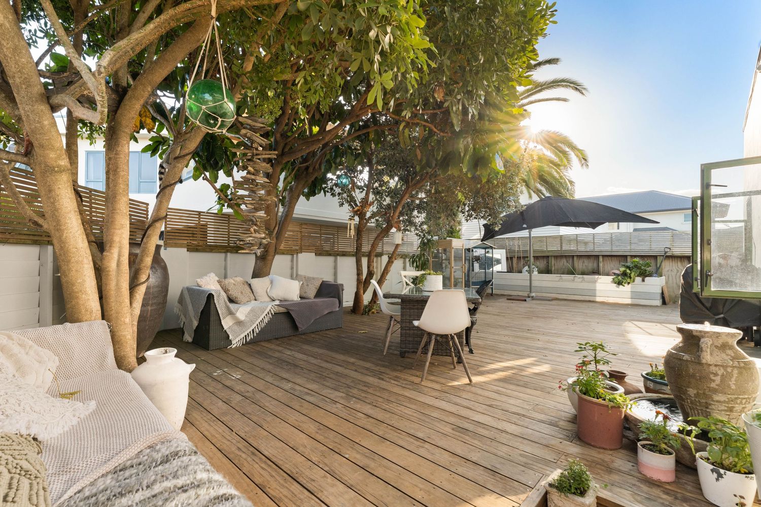 Outdoor terrace with trees and seating area overlooking coastal views.