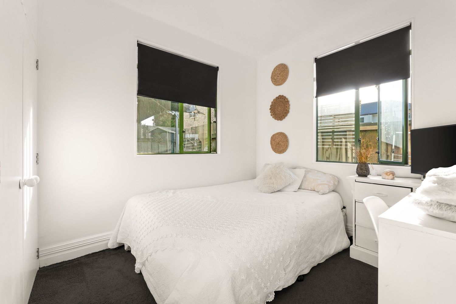 Contemporary bedroom with white bedding and dark window treatments.