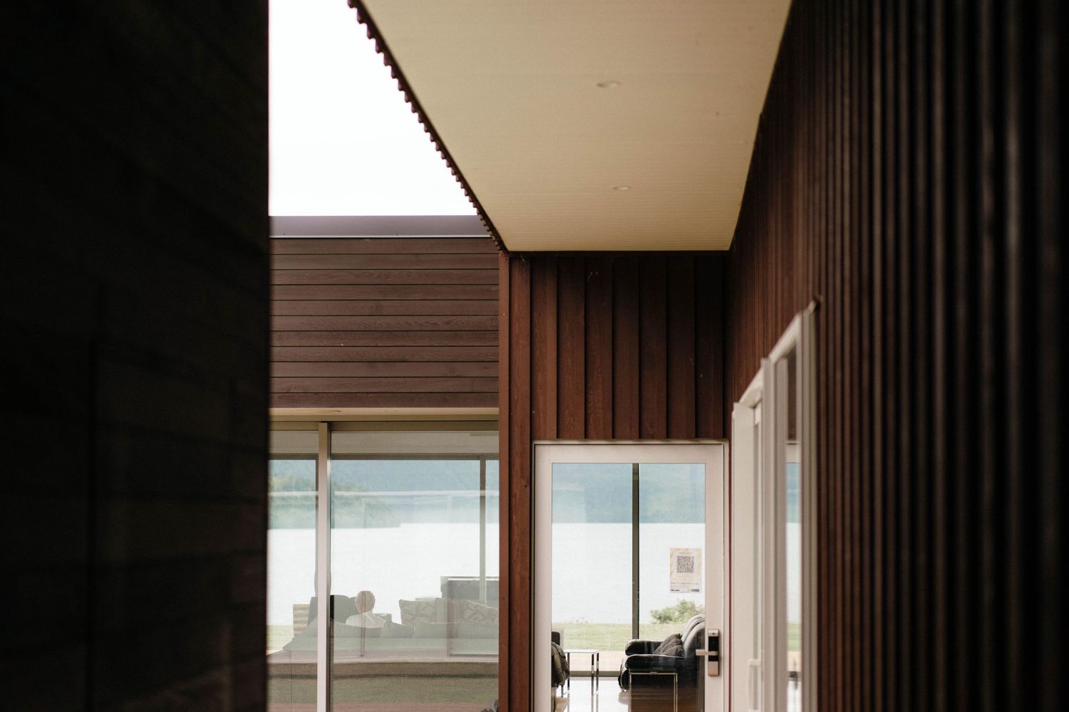 Modern interior hallway with wooden paneling and large windows providing natural light and outdoor views.