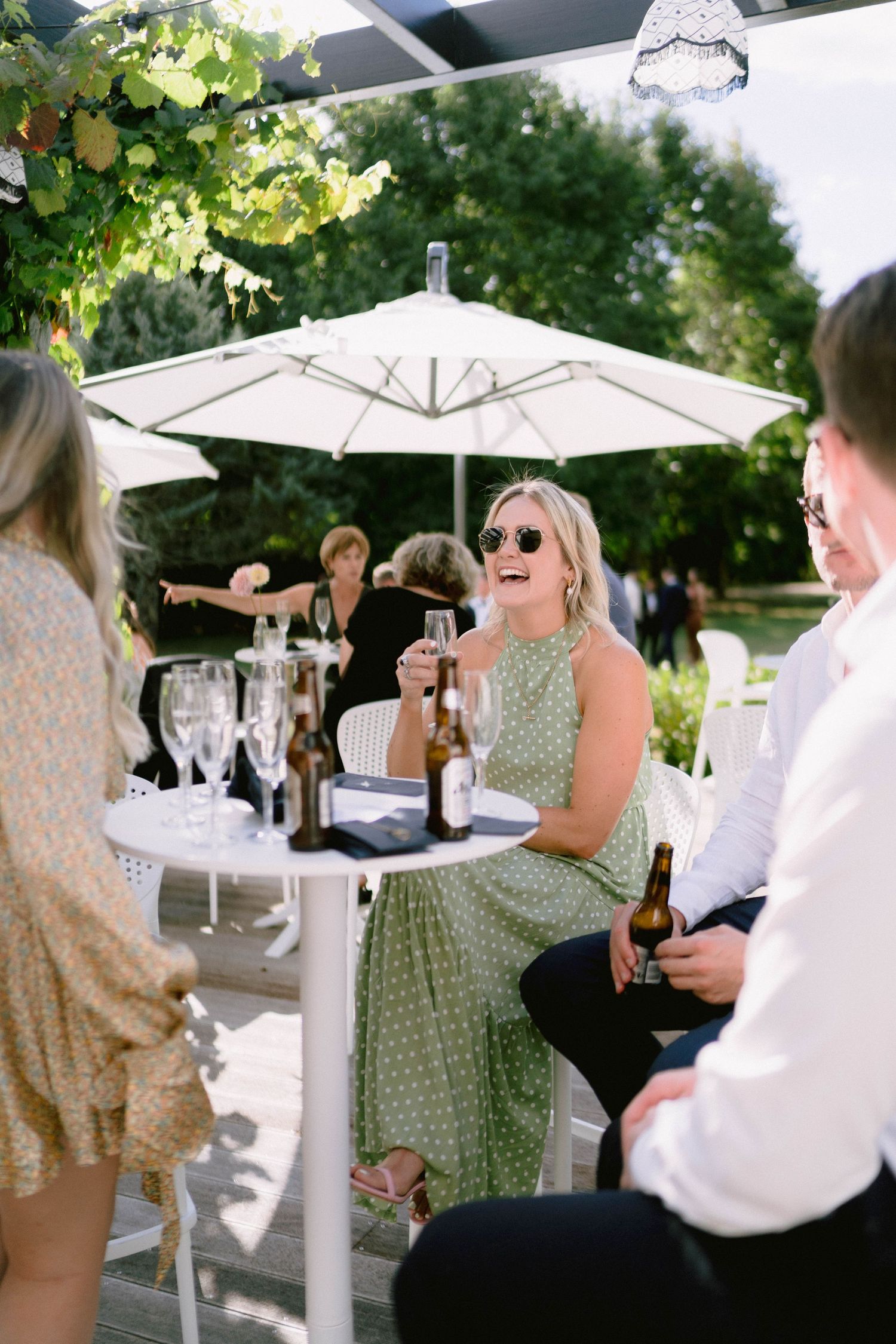 Guests enjoying refreshments under white umbrellas at an outdoor wedding reception.