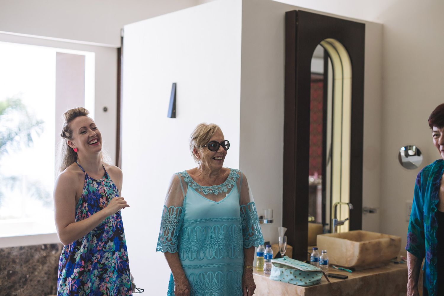 Guests gathered in a bright indoor room wearing formal attire in blue and turquoise tones for a special occasion.