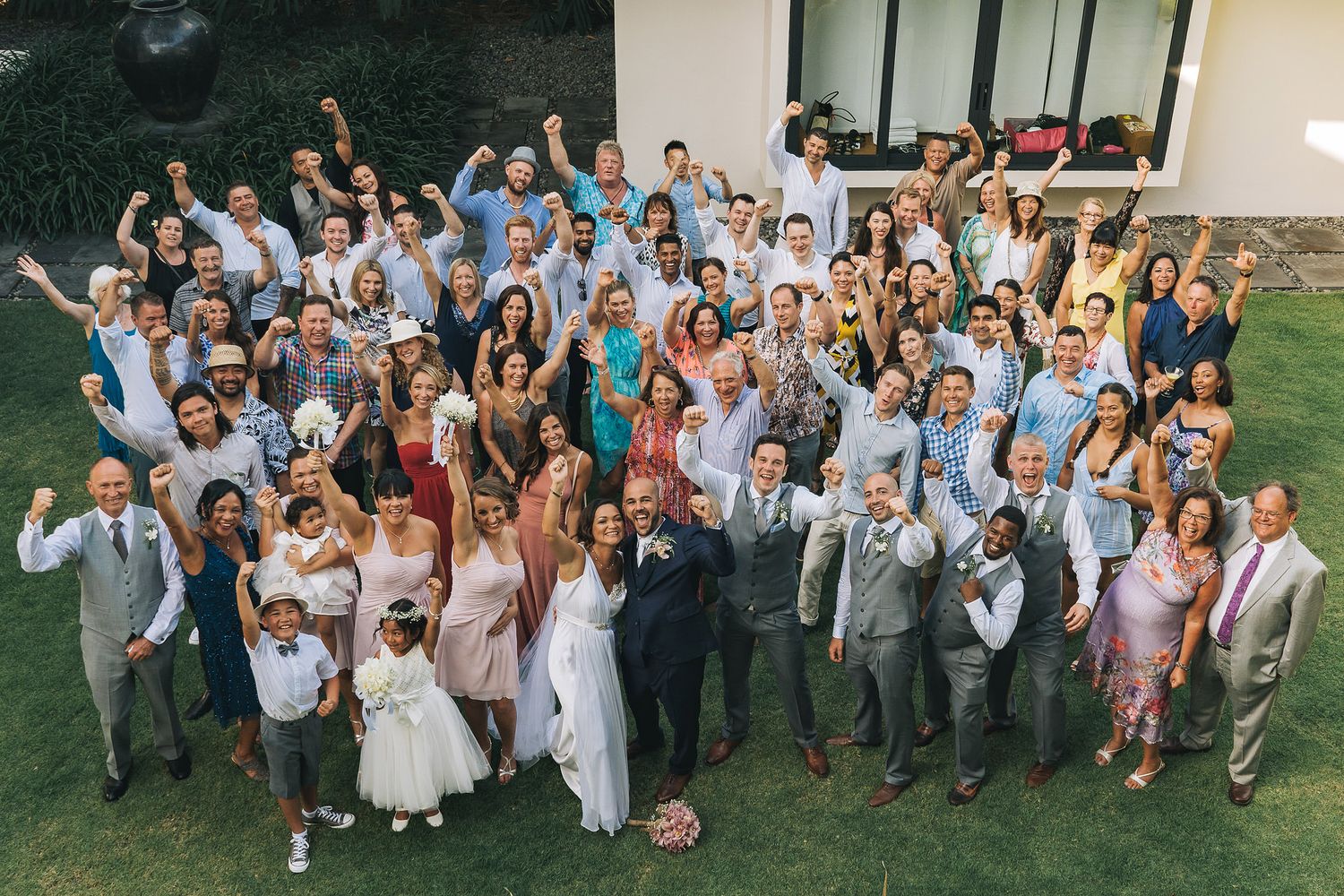 Large group wedding photo of guests and wedding party on a grassy lawn.