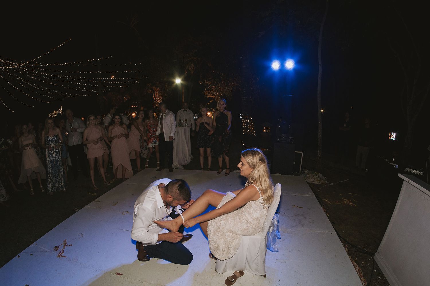 A romantic wedding tradition moment captured on an illuminated outdoor dance floor.