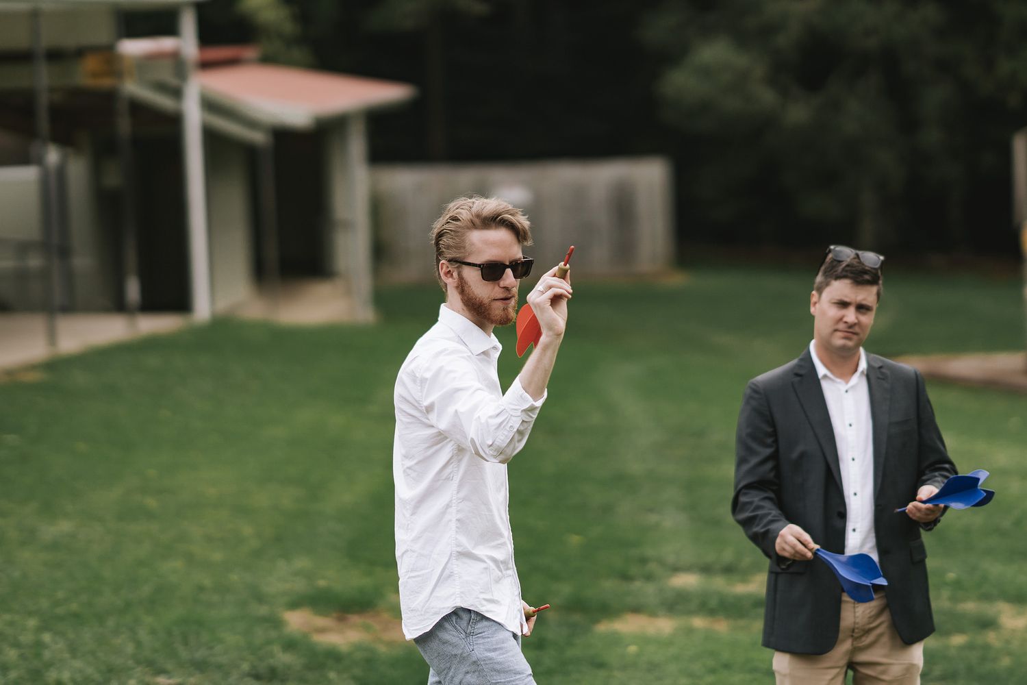 Two professionals in outdoor business setting with sunglasses and tablets at work event.