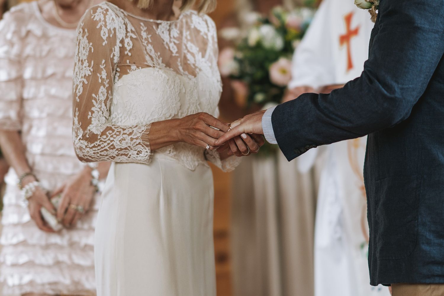 A row of wedding ceremony attendees wearing elegant formal attire standing in line at a decorated indoor venue.