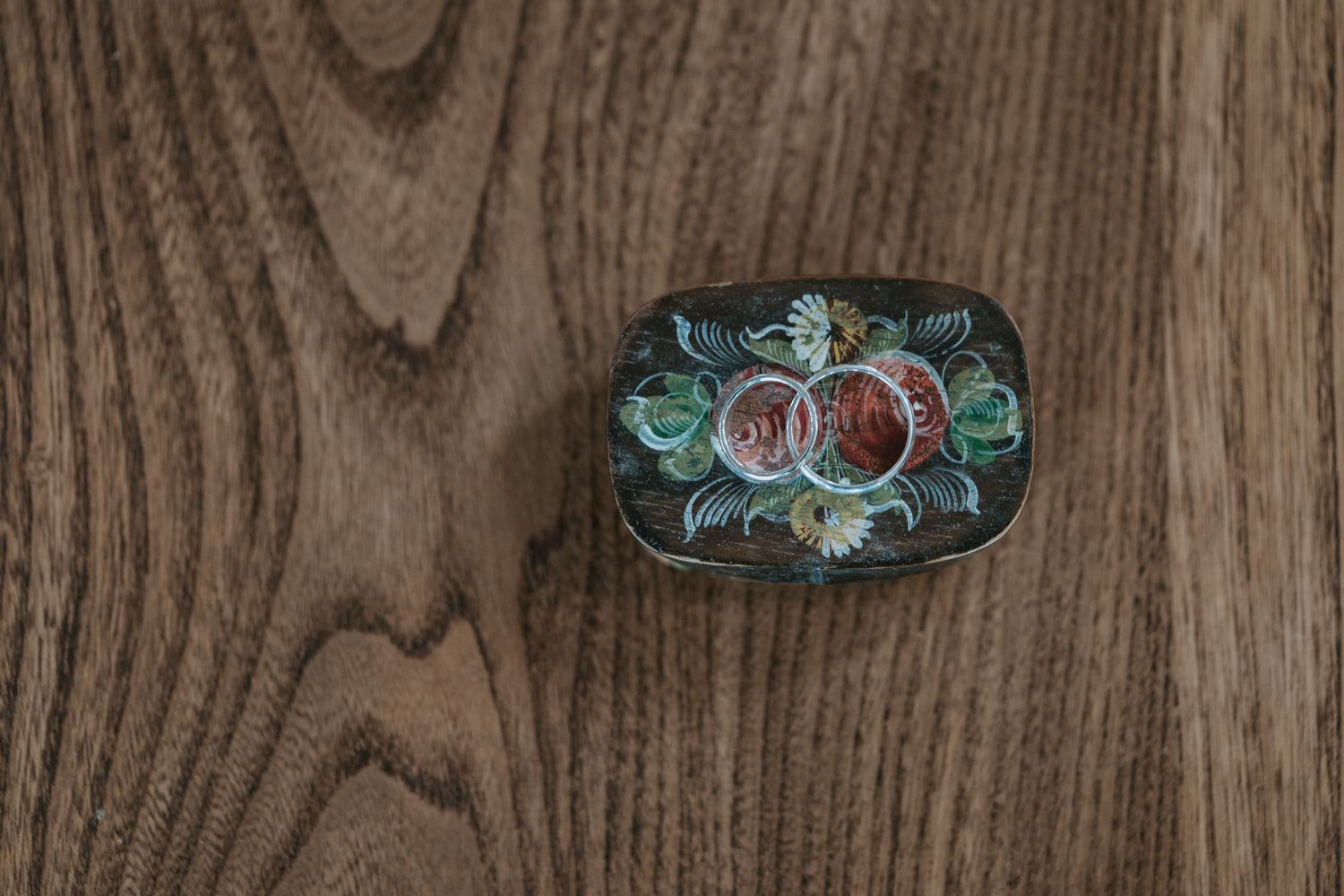 A vintage floral painted tray with pink roses and green leaves on dark wood background.