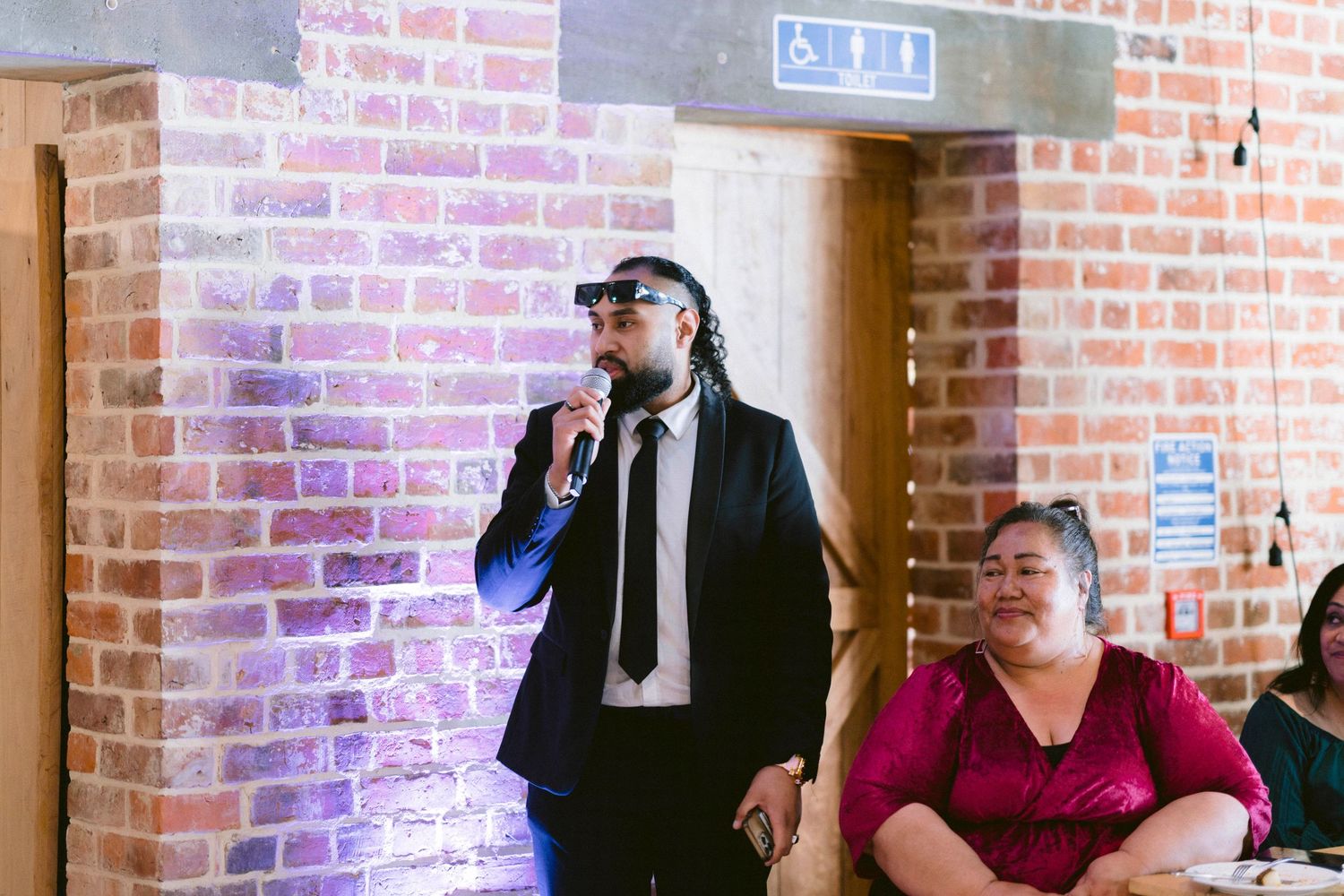 People gathered in a brick-walled indoor venue with exposed brick and industrial styling.