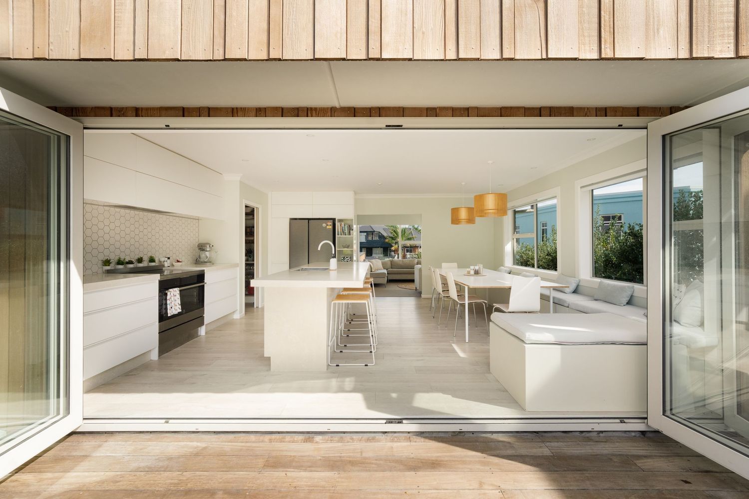 Modern open-plan kitchen and living area with white cabinetry, island bench, and sliding glass doors to outdoor space.