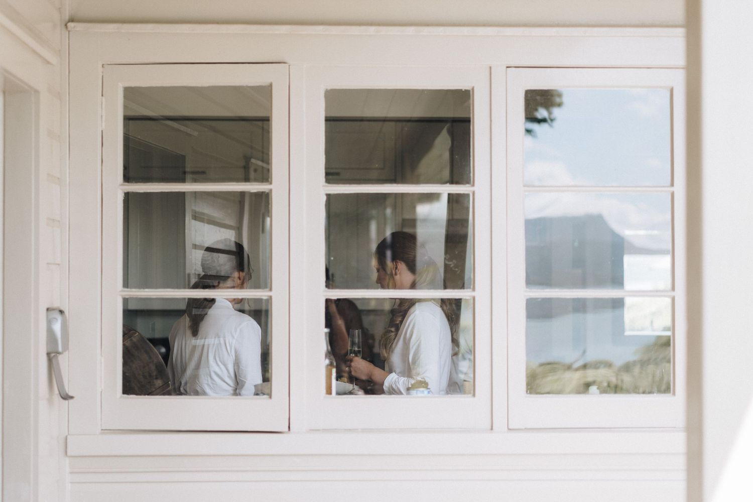 Two figures work in a white-framed window with scenic outdoor views.