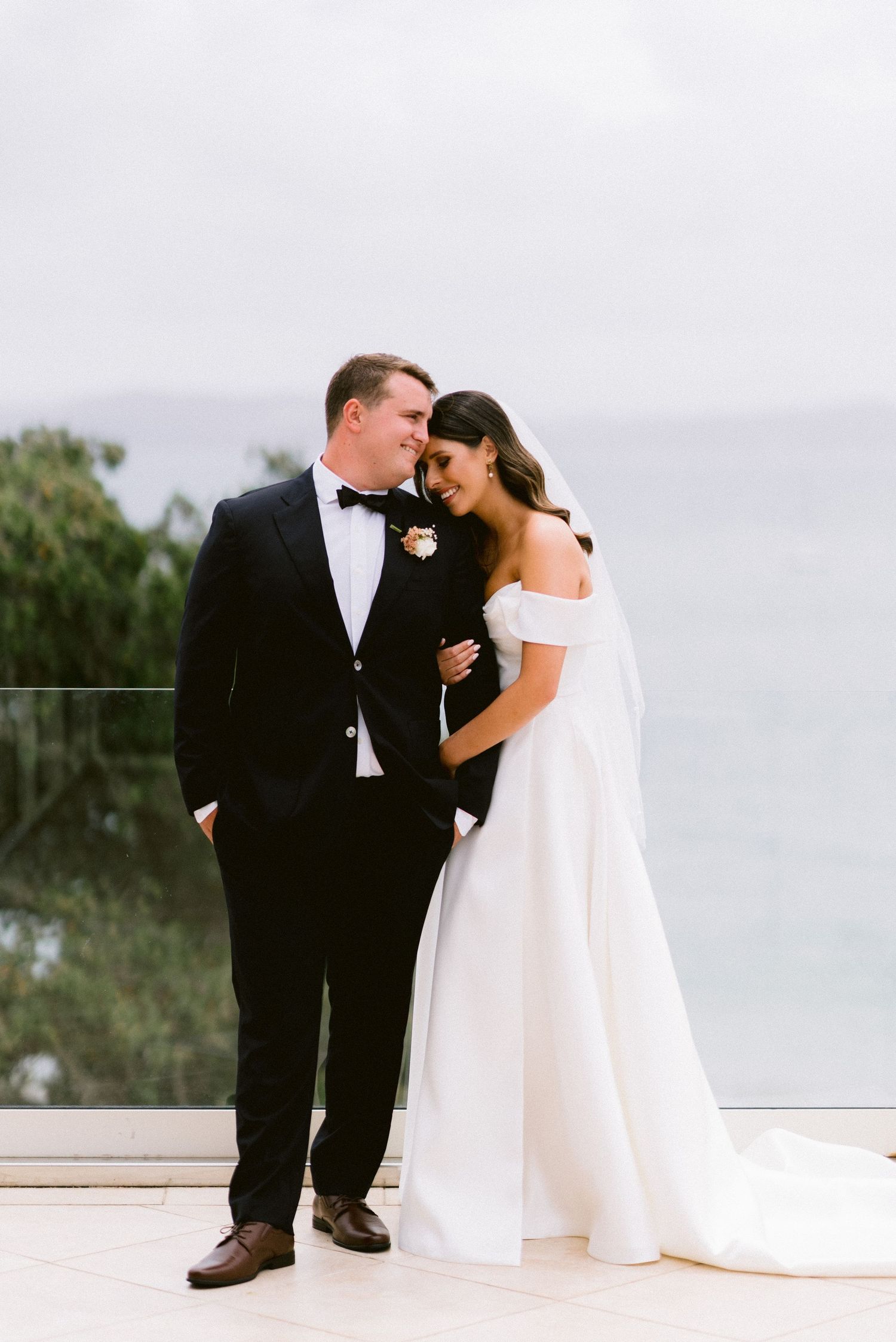 A romantic moment between newlyweds on an oceanfront terrace during their wedding day.